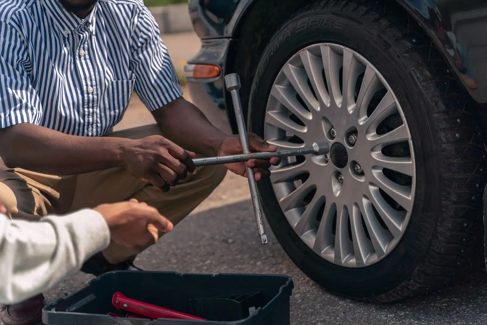 Changing a wheel with a lug wrench at the roadside